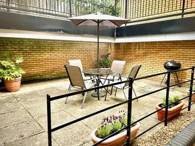 a patio with a table and chairs and an umbrella at Mathus Gardens in Cambridge