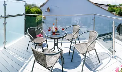 a patio with a glass table and chairs on a deck at Drift In in Aldeburgh