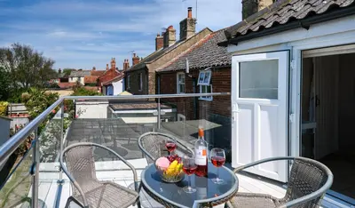 a balcony with a table and chairs and wine bottles at Drift In in Aldeburgh