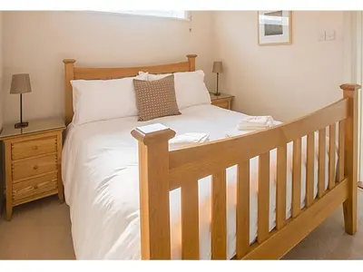 a bedroom with a wooden bed with white sheets at Drift In in Aldeburgh