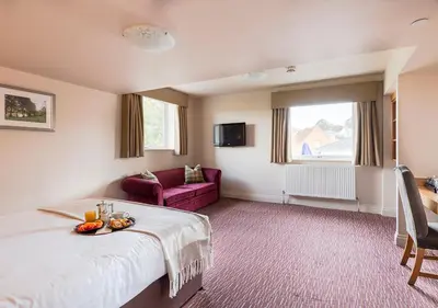 a hotel room with a bed and a couch at The Mill Hotel Sudbury in Sudbury