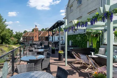 a patio with tables and chairs and a building at The Mill Hotel Sudbury in Sudbury