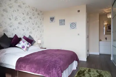 a bedroom with a large bed with a purple blanket at Contemporary & Homely Penthouse, 2 mins walk from Cambridge Station, lift access, secured gated on-site parking, self check-in, SUPER Fast WIFI, Terrace & Sleeps 6 in Cambridge