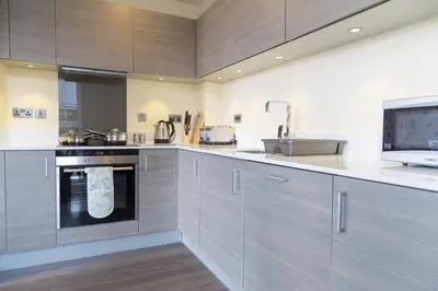 a kitchen with gray cabinets and a sink at Contemporary & Homely Penthouse, 2 mins walk from Cambridge Station, lift access, secured gated on-site parking, self check-in, SUPER Fast WIFI, Terrace & Sleeps 6 in Cambridge