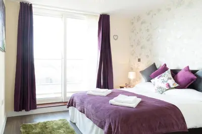 a bedroom with a bed with purple sheets and a window at Contemporary & Homely Penthouse, 2 mins walk from Cambridge Station, lift access, secured gated on-site parking, self check-in, SUPER Fast WIFI, Terrace & Sleeps 6 in Cambridge