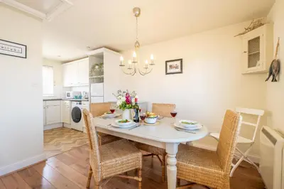a kitchen and dining room with a white table and chairs at 2 Bell Lodge, Thorpeness in Thorpeness