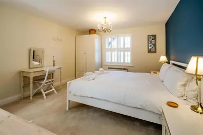 a bedroom with a large white bed and a desk at 2 Bell Lodge, Thorpeness in Thorpeness
