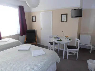 a room with two beds and a table with chairs at Brunton House Guest House in Clacton-on-Sea