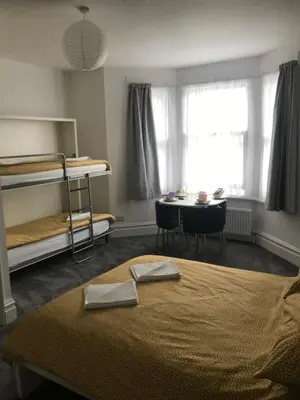 a bedroom with a bed and a desk and a table at Brunton House Guest House in Clacton-on-Sea
