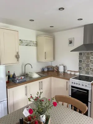 a kitchen with white cabinets and a table with flowers at Chestnut Cottage in East Bergholt