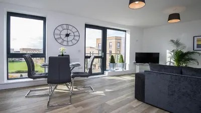 a living room with a couch and a table and a clock at Tailored Stays - De Havilland House in Cambridge