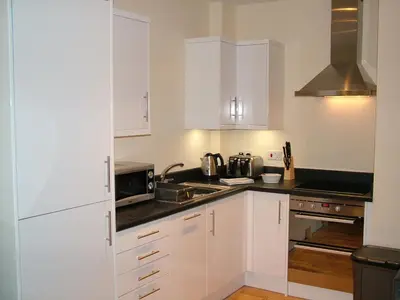 a white kitchen with white cabinets and a sink at Stratford Apartment in Newmarket