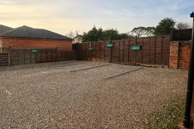 a driveway with a fence with signs on it at The Railway Sleeper Lodge in Colchester