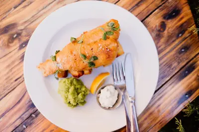 a plate of food with fish and broccoli on a table at The Cricketers Arms in Quendon
