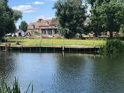 a house on the side of a lake with a dock at Pike & Eel Hotel and Marina in Needingworth