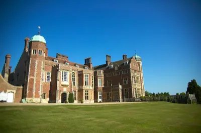 a large brick building with a grass field in front at Madingley Hall in Cambridge
