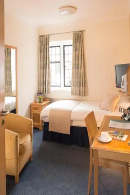 a hotel room with a bed and a desk at Madingley Hall in Cambridge