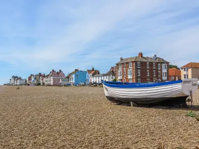 a boat on the beach with houses in the background at Watermans in Aldeburgh