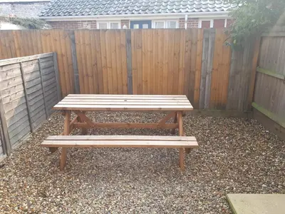 a wooden picnic table in front of a fence at St Giles, Thetford, 2BR House in Thetford