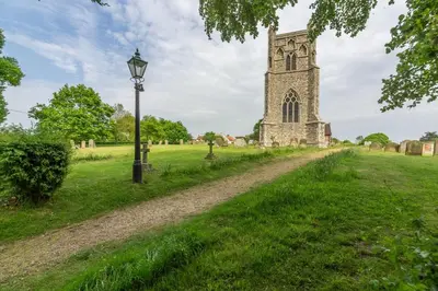 a dirt road in front of a church with a street light at Myrtle Cottage in Friston