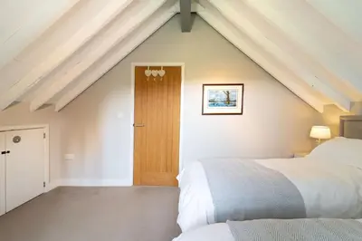 a attic bedroom with two beds and a wooden door at The Dairy in Freston