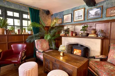 a living room with a fireplace and a chair at Salisbury Arms Hotel in Hertford