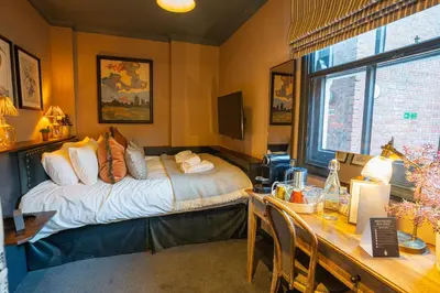 a bedroom with a bed and a desk and a table with chairs at Salisbury Arms Hotel in Hertford