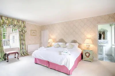 a bedroom with a large white bed with two lamps at Vicarage House & Pool House in Hockham