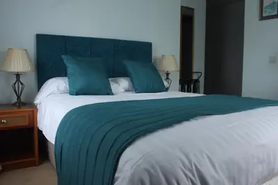 a bedroom with a large bed with a blue headboard at The Crown House Inn in Great Chesterford