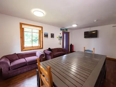 a living room with a table and a couch at YHA London Lee Valley in Cheshunt