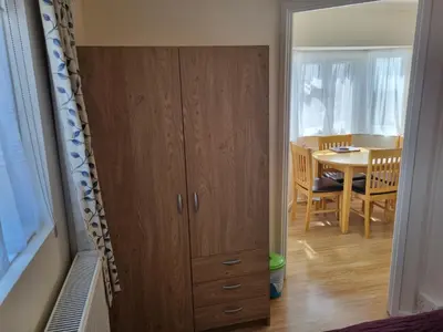 a room with a wooden cabinet and a dining room at Sandy Cottage in Clacton-on-Sea