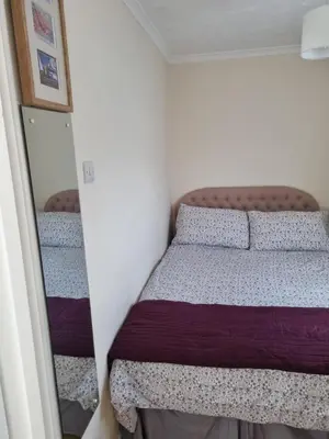 a small bedroom with a bed and a mirror at Sandy Cottage in Clacton-on-Sea