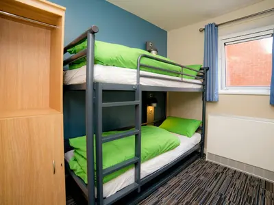 a bunk bed room with two bunk beds with green pillows at YHA Cambridge in Cambridge