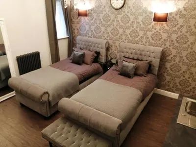 a room with two beds and a couch and a clock at Apartments at Number 10 The Abbey in Norwich