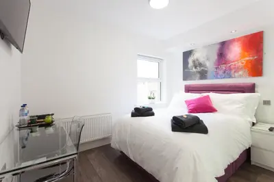 a bedroom with a white bed with pink accents at The Orlando in Cambridge