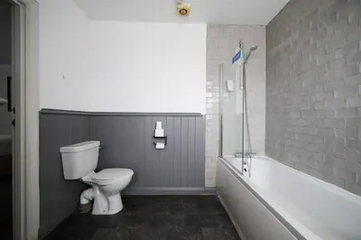 a bathroom with a white toilet and a bath tub at White Hart, Newmarket by Marston's Inns in Newmarket