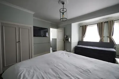 a bedroom with a large white bed and a couch at White Hart, Newmarket by Marston's Inns in Newmarket