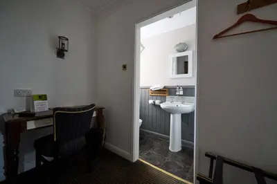 a bathroom with a sink and a toilet and a chair at White Hart, Newmarket by Marston's Inns in Newmarket