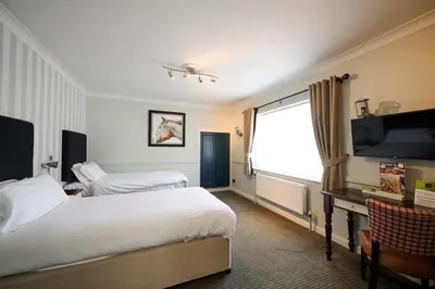 a hotel room with two beds and a flat screen tv at White Hart, Newmarket by Marston's Inns in Newmarket