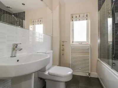 a white bathroom with a toilet and a sink at Sandlings in Hollesley