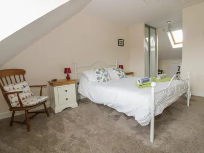 a bedroom with a white bed and a chair at Sandlings in Hollesley