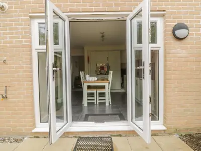 an aluminium conservatory door with a table in a room at Sandlings in Hollesley