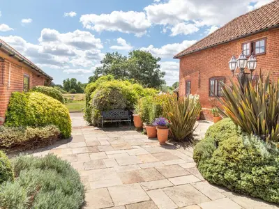 a garden with potted plants and a brick building at Horseshoe in Little Glenham