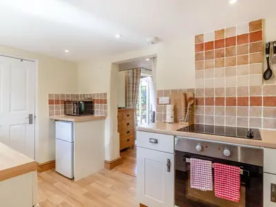a kitchen with white cabinets and a stove top oven at Norbank Cottage in Bressingham