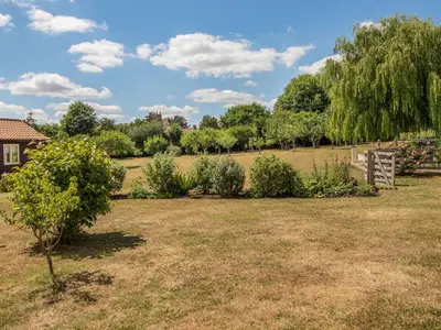 a garden with bushes and trees in a field at Norbank Cottage in Bressingham
