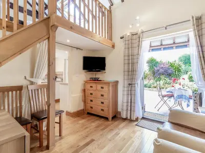 a living room with a staircase and a tv at Norbank Cottage in Bressingham