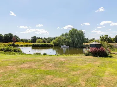 a pond with a gazebo in a park at Punch Cottage in Little Glenham