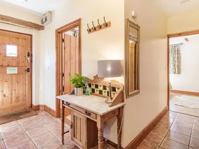 a hallway with a wooden table and a mirror at Punch Cottage in Little Glenham