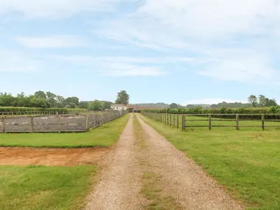 a dirt road in a field with a fence at Tawny Owl Barn in Shipdham