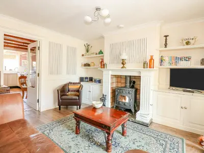 a living room with a table and a fireplace at Cameron's Cottage in Swaffham